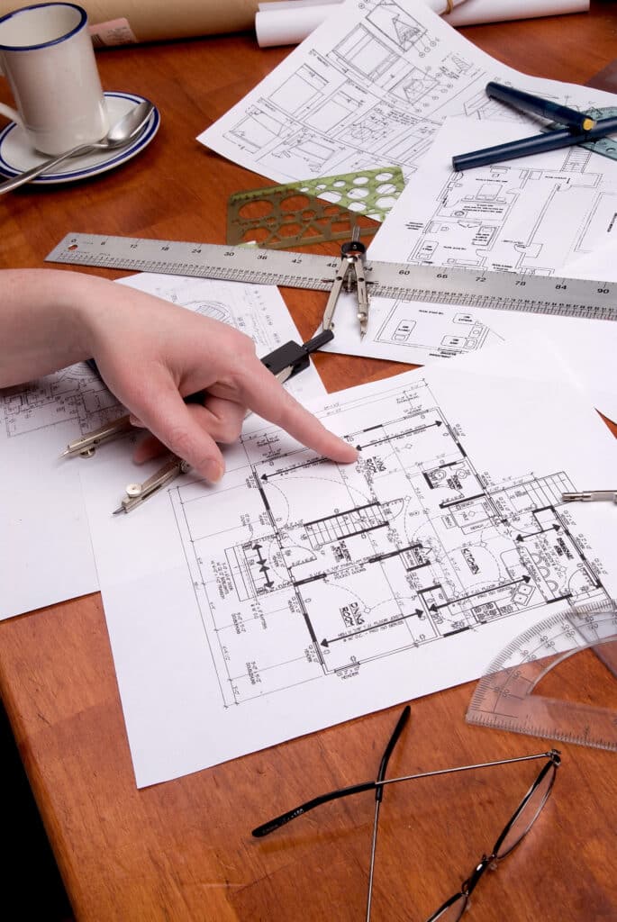 woman engineer, architect or contractor works on p Une personne tenant une règle examine des plans dans un cabinet d'architecte.